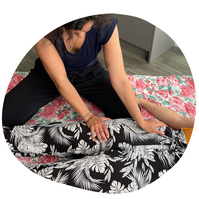 une praticienne en shiatsu applique des pressions sur la jambe de la receveuse.